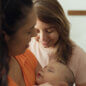 lesbian couple looking at sleeping baby in the living room.